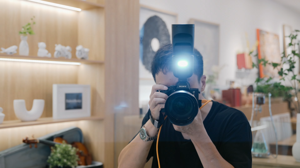 A photographer taking a picture using a camera with a speedlight flash attached