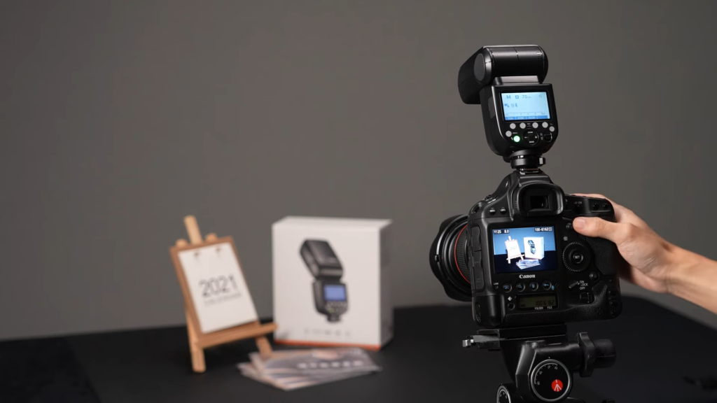 a photographer using a camera with a speedlite flash attached for product photography