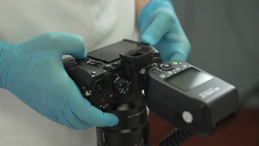 a doctor holding a Sony camera with MF-R76S+ round flash attached