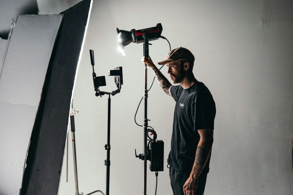 Lighting technician gaffer holding a COB LED light fixture on a set