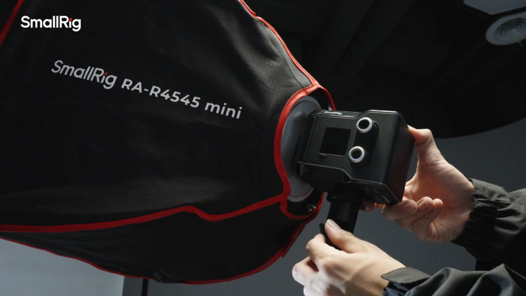 A filmmaker is setting up the SmallRig RC 60C COB RGB LED video light with softbox on a light stand