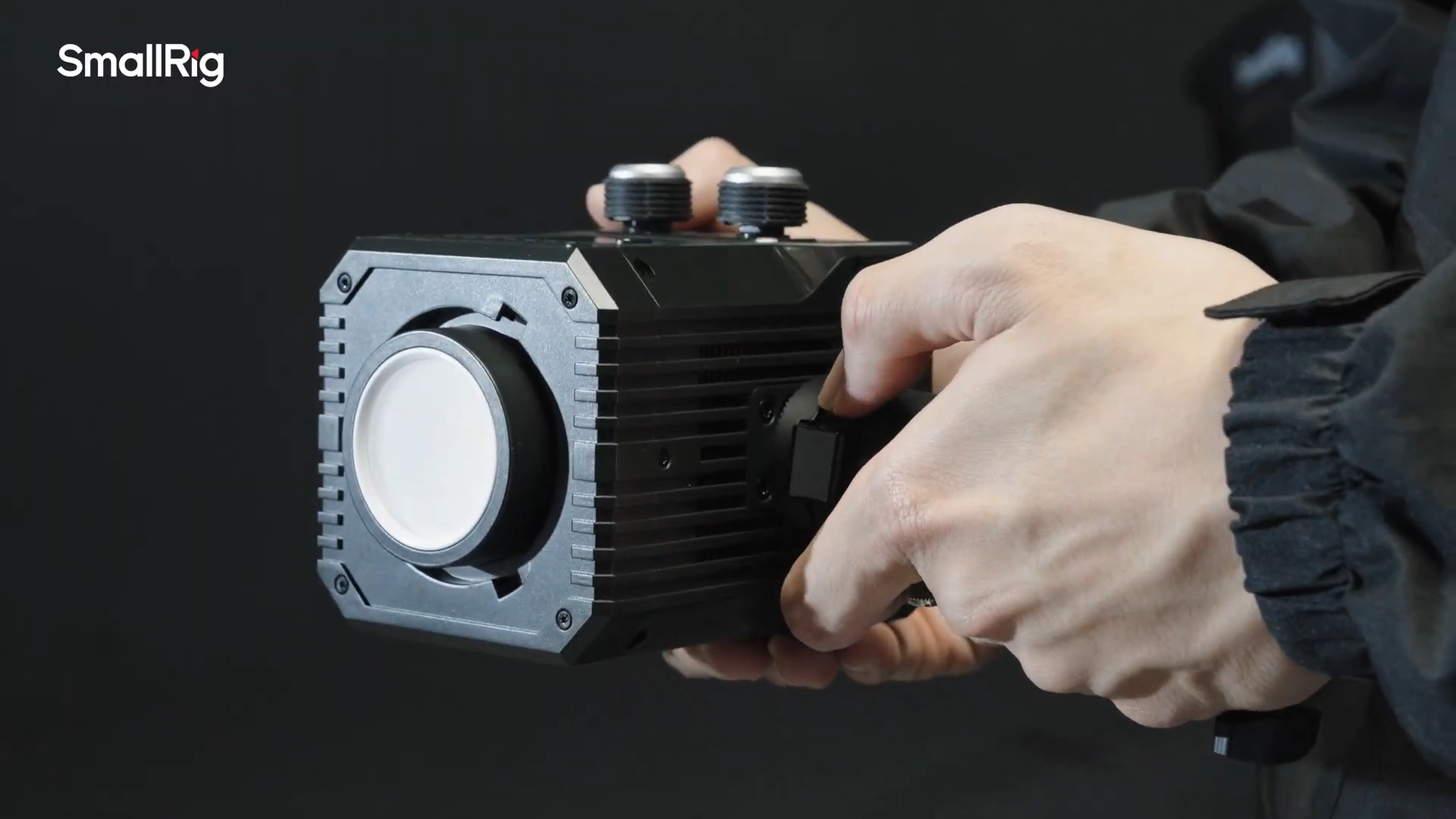 A man is holding the SmallRig RC 60C COB RGB LED video light in his hands setting it up for shooting