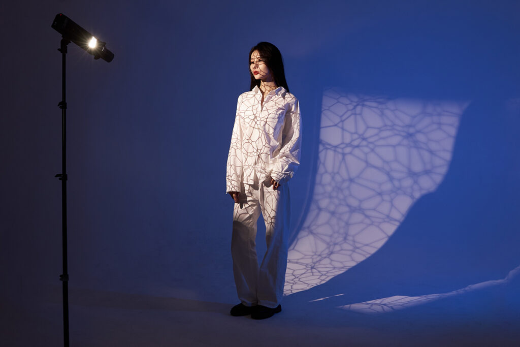 Model posing in studio on blue background in front of Godox AD200 with AK-R21 projection attachment 