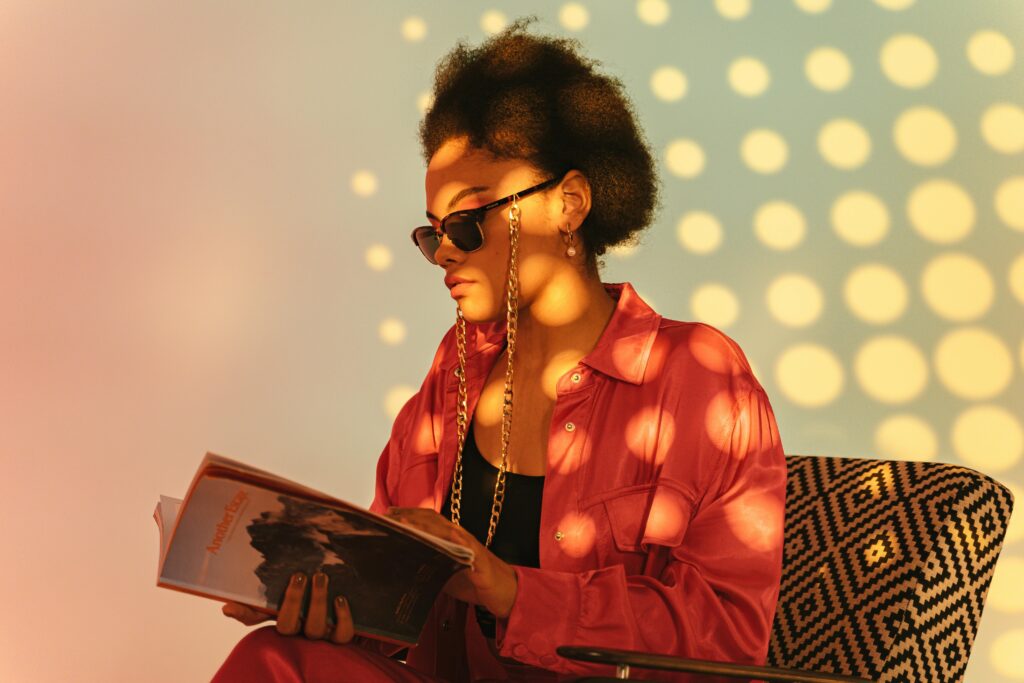 Portrait of a woman in sunglasses reading a book in an armchair lit with dotted gobo effect 