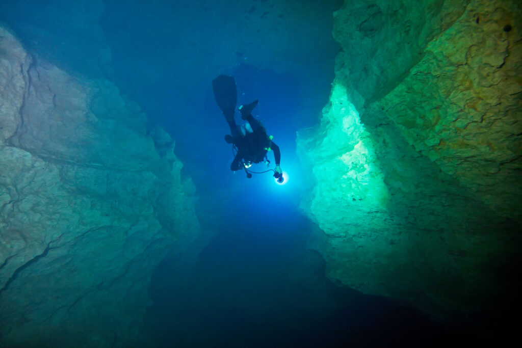 a deep sea scuba diver diving with a strong light on