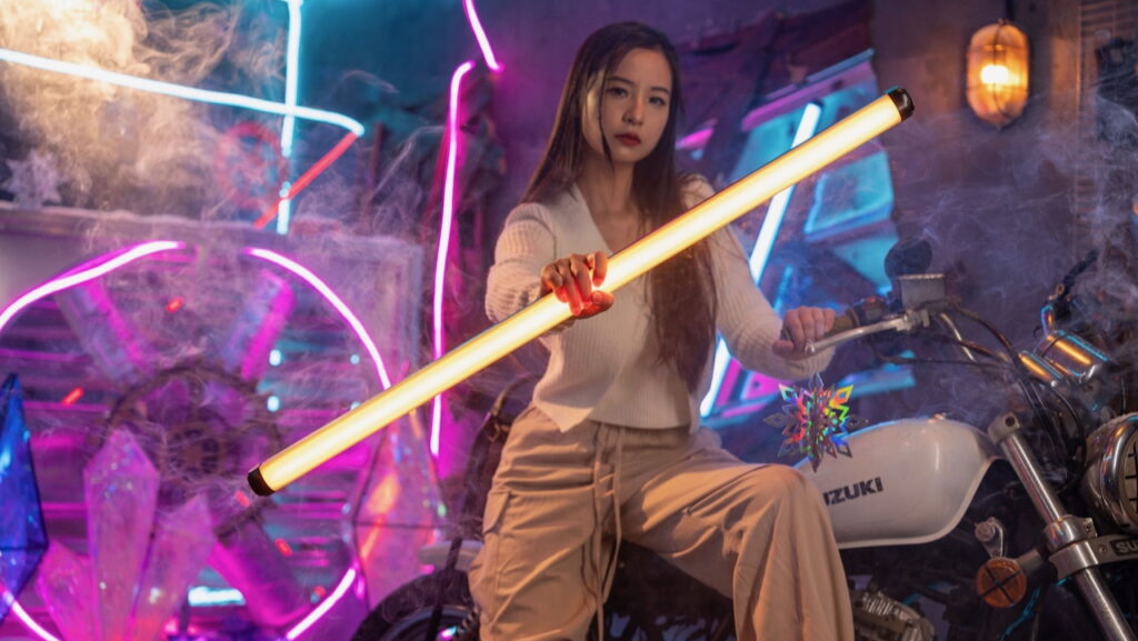 Model posing in a studio holding  Viltrox K90 RGB LED tube light in her outstretched hand